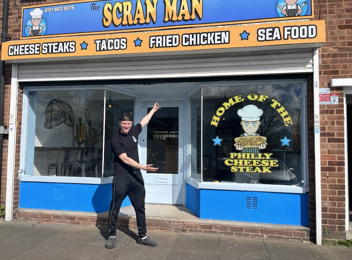 Blake pointing to The Scran Man shopfront